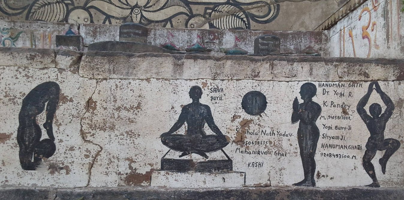 Sylwetki w pozycjach jogi na murze w Varanasi